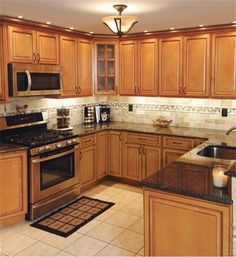 a kitchen with wooden cabinets and granite counter tops, stainless steel appliances and an oven