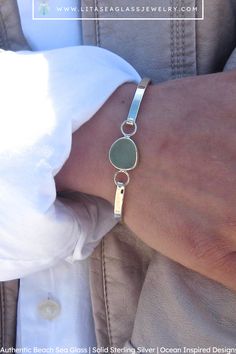 $118.00 ~ This bracelet features a lovely piece of sea glass at its center and a sleek sterling silver hinge-style bracelet. Select your desired sea glass color, shown here in seafoam, to personalize this bracelet. Each bracelet comes in a custom gift box, tied with a bow and ready for gift giving! An upgrade to deluxe gift wrapping is available at checkout. Beach Glass Bracelet Jewelry, Handmade Sea Glass Bracelet For Gift, Bezel Set Sea Glass Jewelry, Silver Sea Glass Jewelry For Beach, Sea Glass Anklet, Adjustable Ocean-inspired Sea Glass Jewelry, Sea Glass Ring, Sea Glass Colors, Sea Glass Bracelet