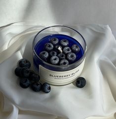 blueberries are in a bowl on a white cloth