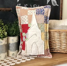 a decorative pillow is sitting on a shelf next to some potted plants and a chalkboard