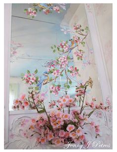 a vase with pink flowers in front of a mirror on the wall next to a window