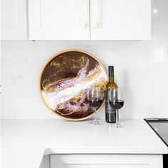 a wine glass and bottle sitting on a counter top next to a white kitchen cabinet