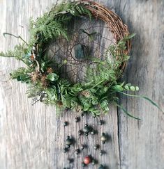 a wreath made out of branches and leaves on top of a wooden table next to berries