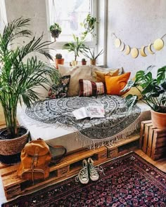 a living room filled with lots of plants and pillows on top of a wooden floor