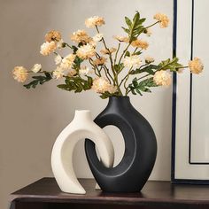 a black and white vase with flowers in it on a table next to a mirror