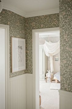 an open door leading to a bedroom with floral wallpaper