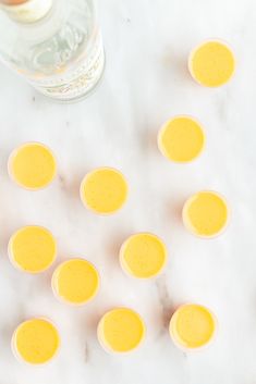 there are many small yellow eggs on the table next to a bottle of water and an egg shell