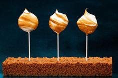 three lollipops sitting on top of a piece of bread with white icing