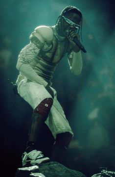 a football player holding a microphone on top of a rock in front of a crowd