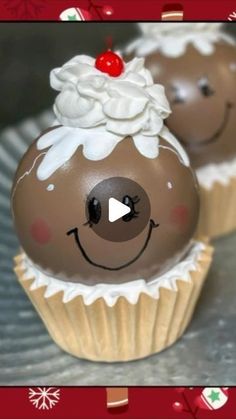 two chocolate cupcakes with white frosting and a cherry on top, decorated in the shape of a reindeer's head