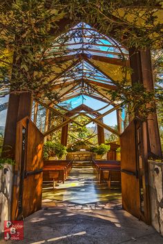 an open door leading into a covered area with benches and trees on either side of it