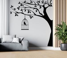 a bird in a cage hanging from a tree wall decal on a living room wall