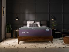 a purple mattress sitting on top of a wooden bed frame