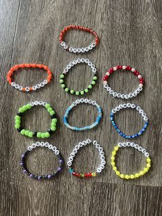 six bracelets with different colored beads on a wooden surface, all lined up in the same row