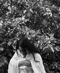 black and white photograph of a woman wrapped in a shawl with flowers behind her