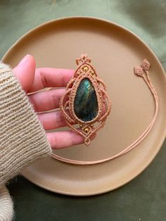 a person holding a piece of wire with a stone in it on top of a plate