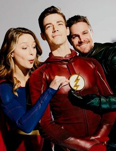 the flash and supergirls are posing for a photo in their costume outfits, with one arm around the other's chest