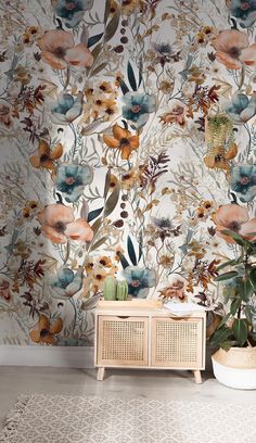 a floral wallpaper with large flowers and plants on the sideboard in front of it