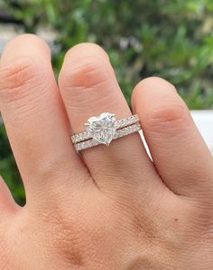 a woman's hand with a diamond ring on top of her finger and the other hand holding an engagement ring