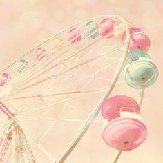 a ferris wheel with pink and blue balls on it's rim, against a pastel background