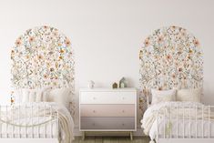 two white beds with floral headboards against a wallpapered background in a bedroom