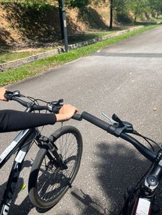 a person riding a bike down a street next to grass and trees on either side of the road