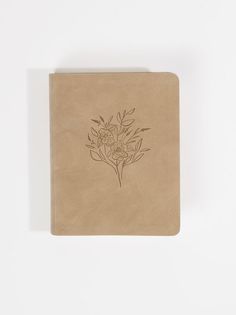 a small notebook with a drawing of flowers on the front and back cover, sitting on a white surface