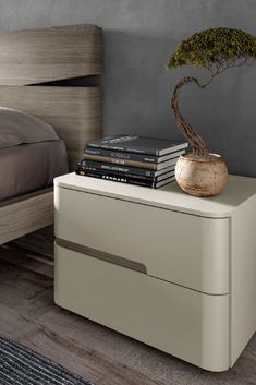 a small bonsai tree sits on top of a white nightstand next to a bed