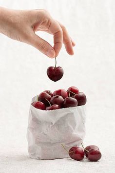 a person is picking up some cherries from a bag with the words hand picked magic tricks