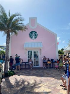 people standing in front of a pink building with a starbucks sign on it's side