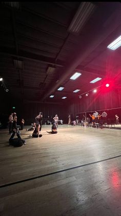 a group of people riding skateboards on top of a wooden floor in a warehouse