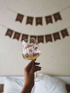 a person holding up a wine glass with the words today is your day written on it