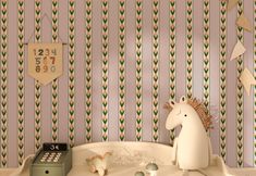 a toy horse sitting on top of a bath tub next to a wallpapered background