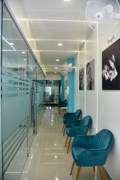 a long hallway with blue chairs and pictures on the wall