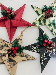 christmas decorations made out of folded paper and pine cones are hanging on a white wall