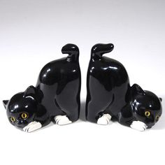 two black cat figurines sitting next to each other on a white table top