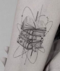 a woman with a tattoo on her arm is holding a stack of books