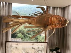 a wooden fish hanging from the ceiling in front of a window