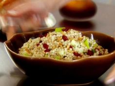 a brown bowl filled with food sitting on top of a table next to a person