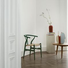 two chairs and a table with vases on them in a white walled room next to a door