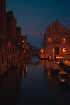 boats are parked along the side of a canal at night