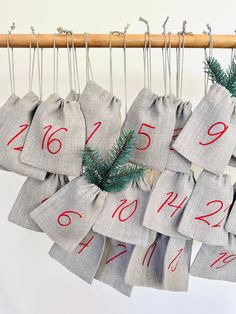 christmas stockings hanging from a wooden hanger with red numbers and evergreen needles on them