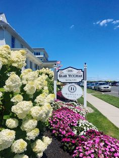 the sign for grand victoria is surrounded by flowers and shrubs in front of a building