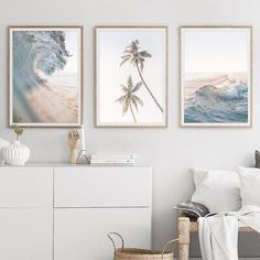 three framed pictures hang on the wall above a bed in a room with white furniture