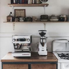 a coffee maker sitting on top of a wooden counter next to a white stove top oven