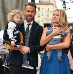 a man in a suit and tie holding two children while standing next to a woman