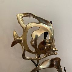 a metal sculpture with two fish on it's legs and one in the shape of a human head