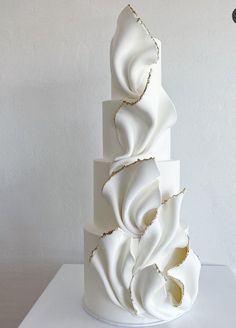 a three tiered white cake with gold decorations