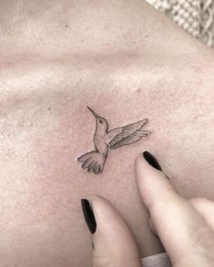 a woman's chest with a hummingbird tattoo on it