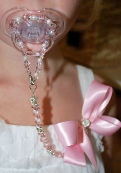 a woman wearing a pacifier with pearls and a pink bow